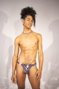 Person wearing a black thong with pink and white patterns against a plain background