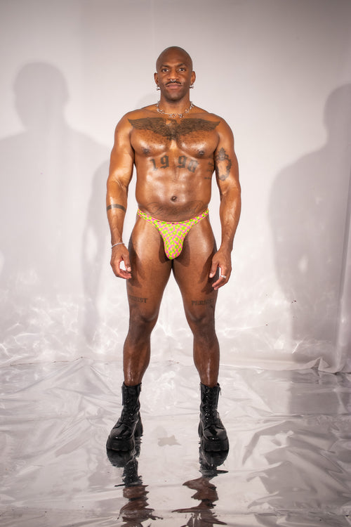 Man wearing a yellow thong against a plain background