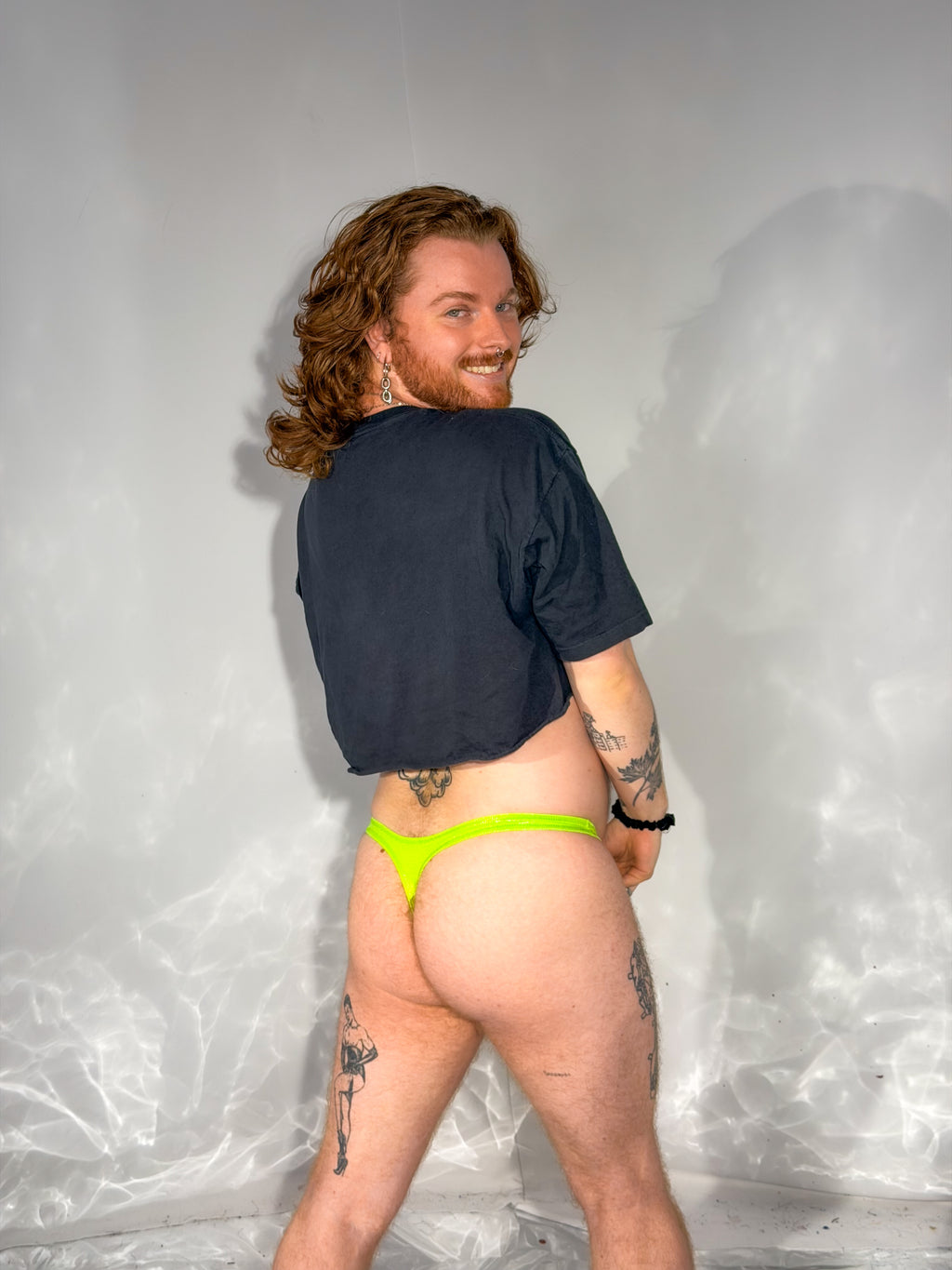 Person wearing a black shirt and bright green underwear against a plain background
