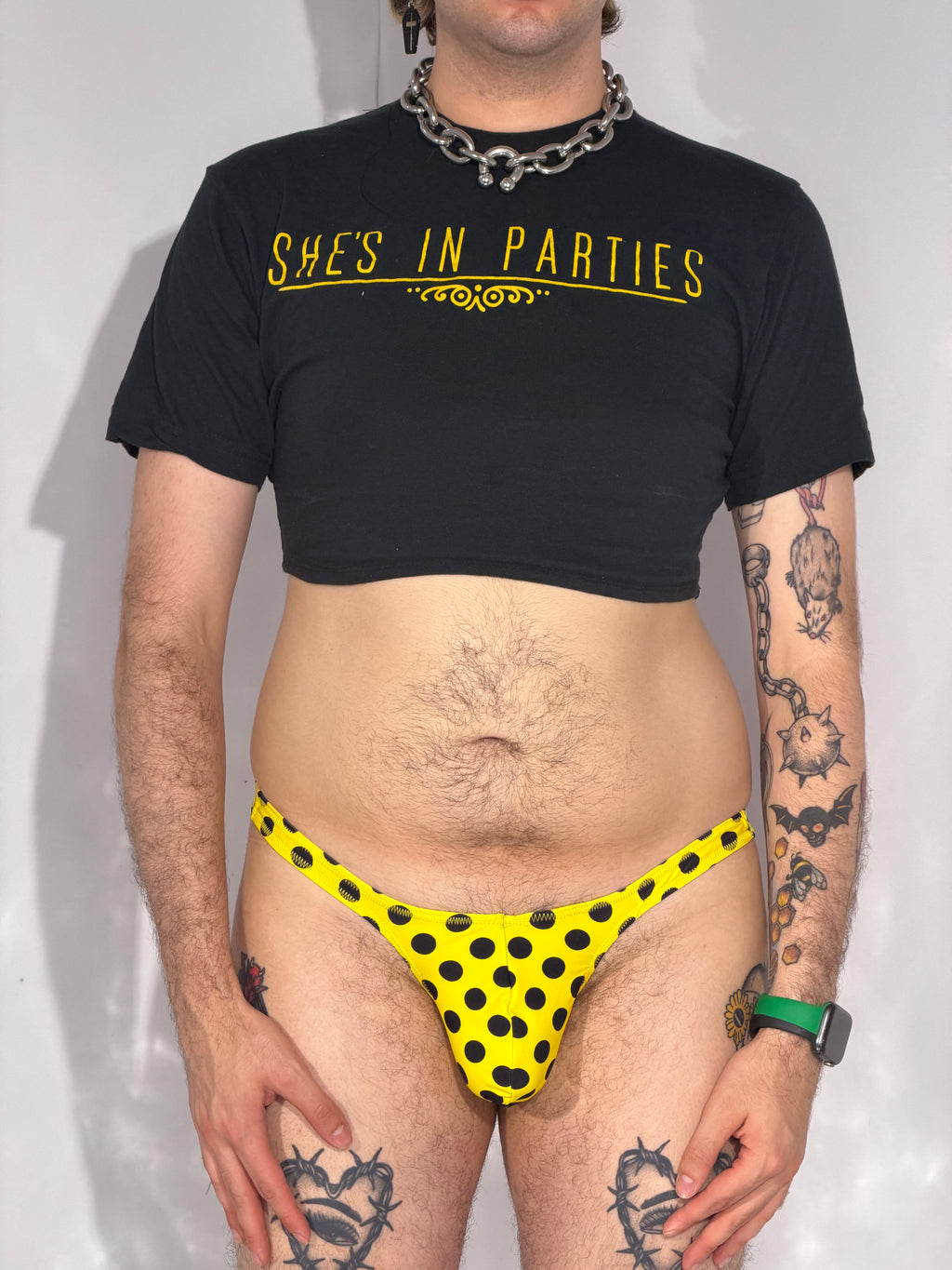 Person wearing a black t-shirt with 'SHE'S IN PARTIES' text and yellow polka dot underwear.