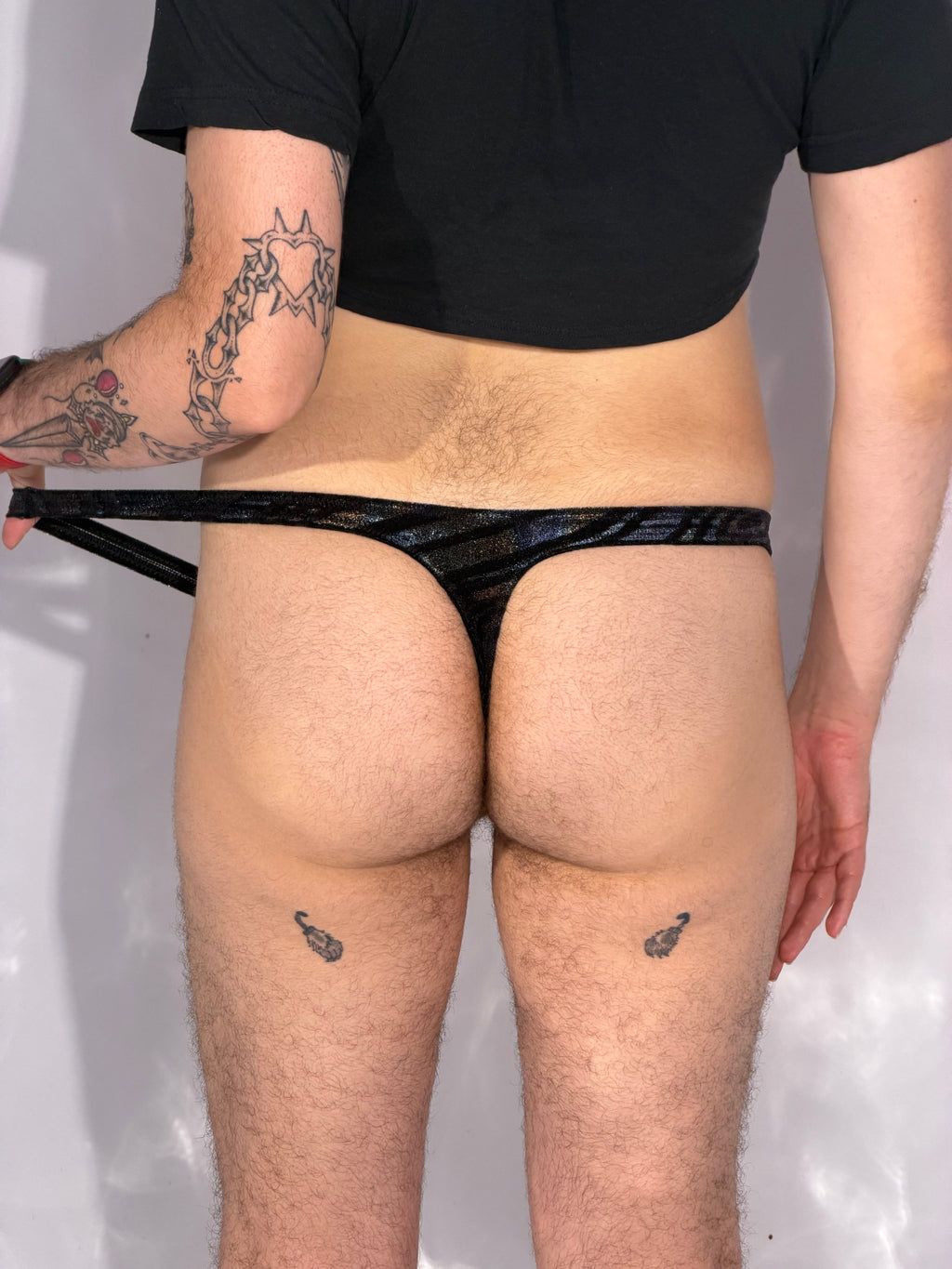 Person wearing black underwear with a plain background