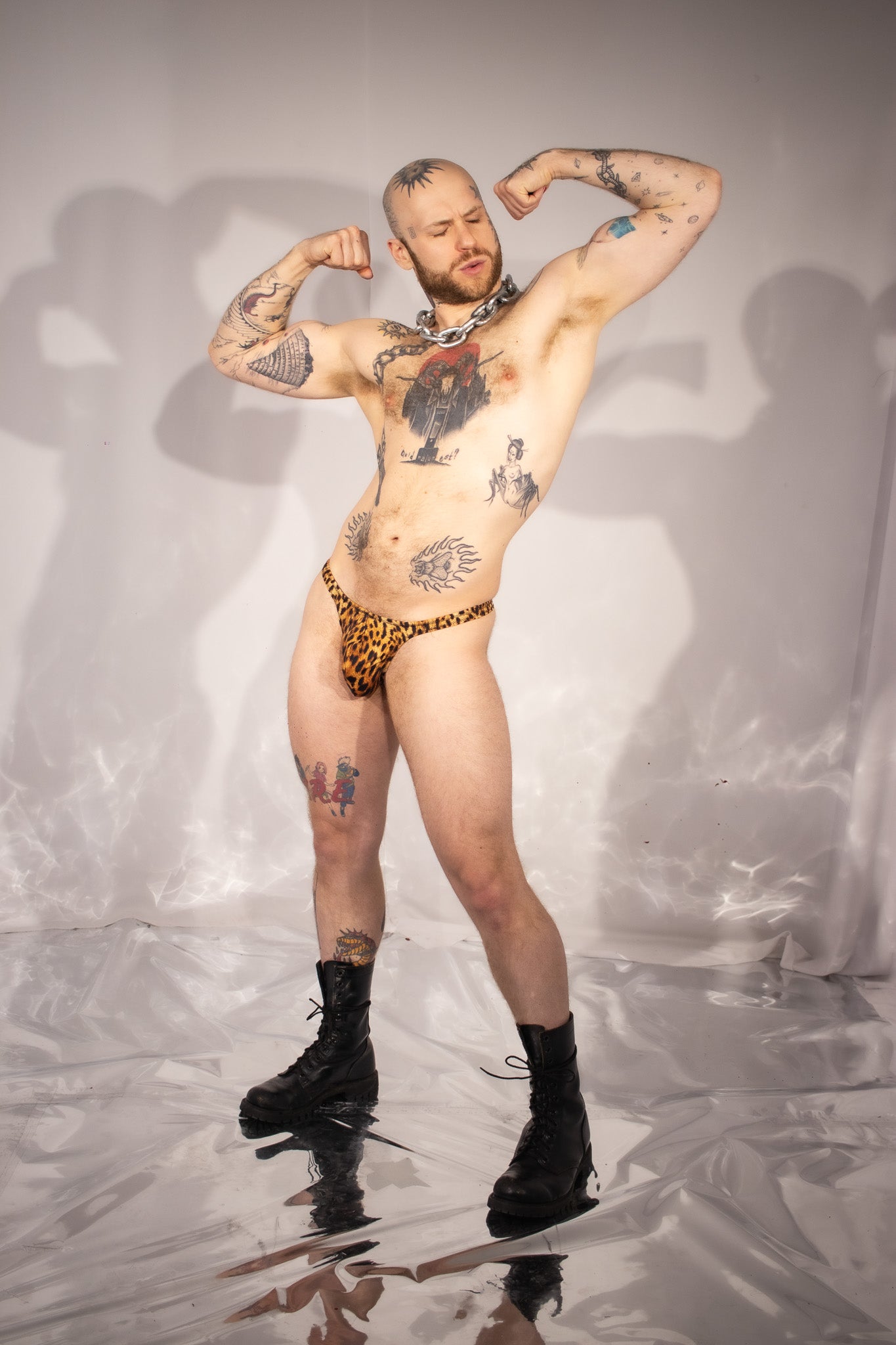 Man with tattoos wearing leopard print underwear on a reflective surface